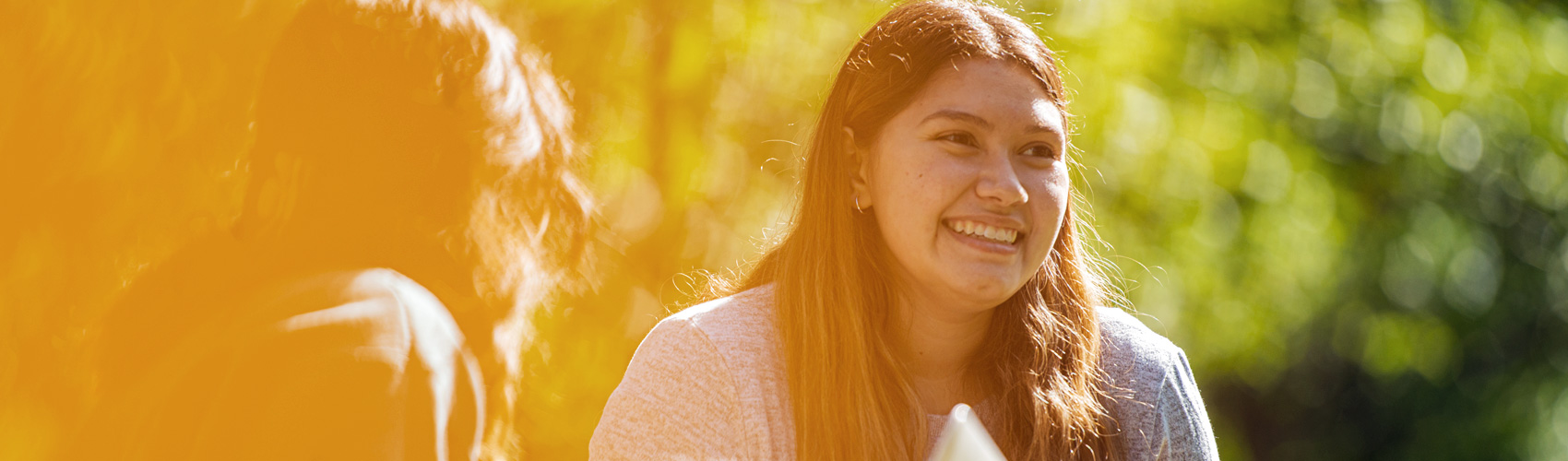 girl sitting with another student in the grass, smiling